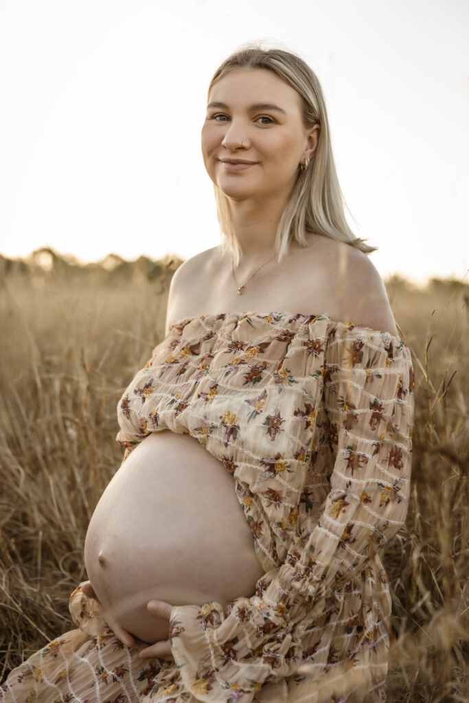 Pregnant Mum sitting in a dry wheat field