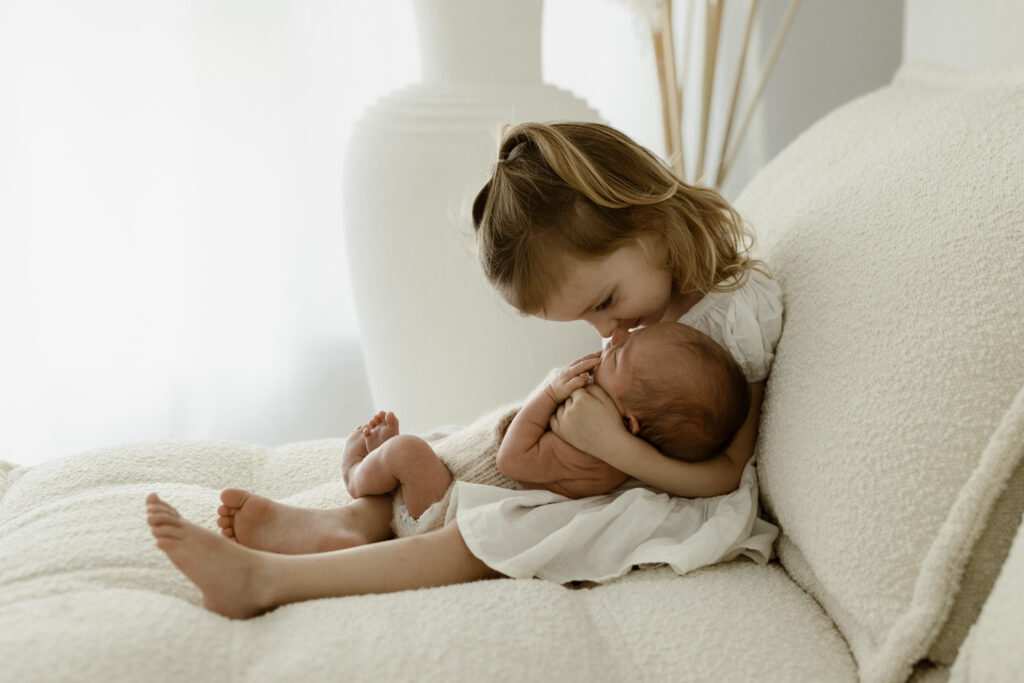 Big sister cuddling her newborn brother. 