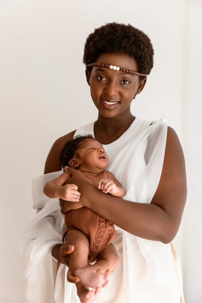 Mum holding bub, while looking at the camera. She is wearing cultural attire.